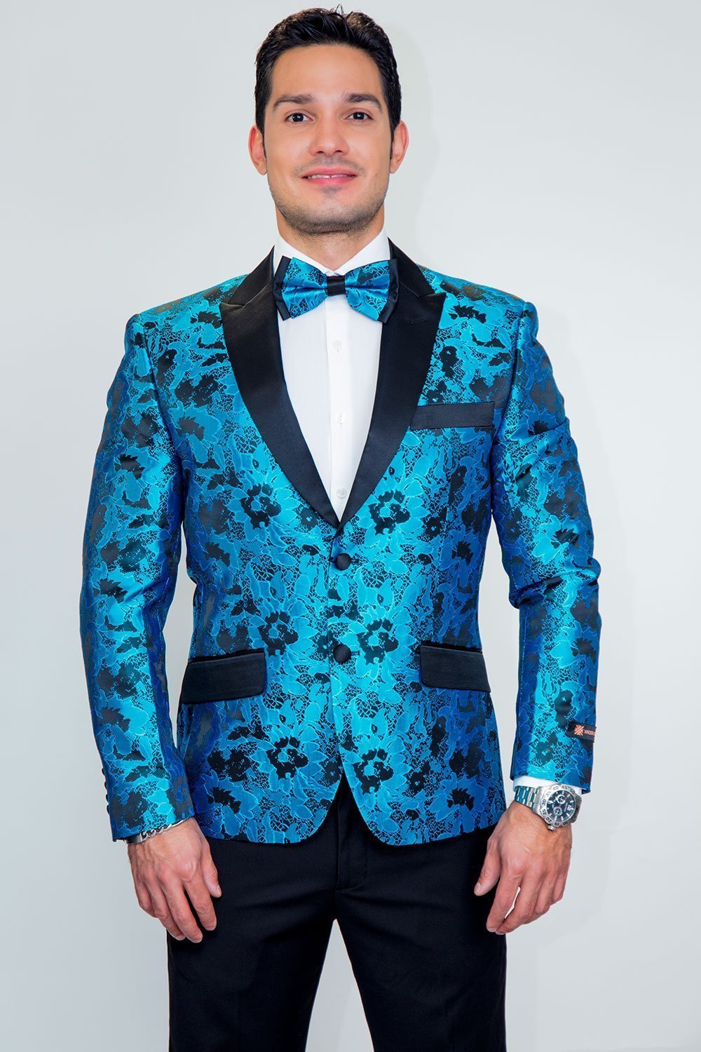 Amsterdam Tuxedo Jacket Peak in turquoise floral with black satin peak lapels, one-button, worn by a man.
